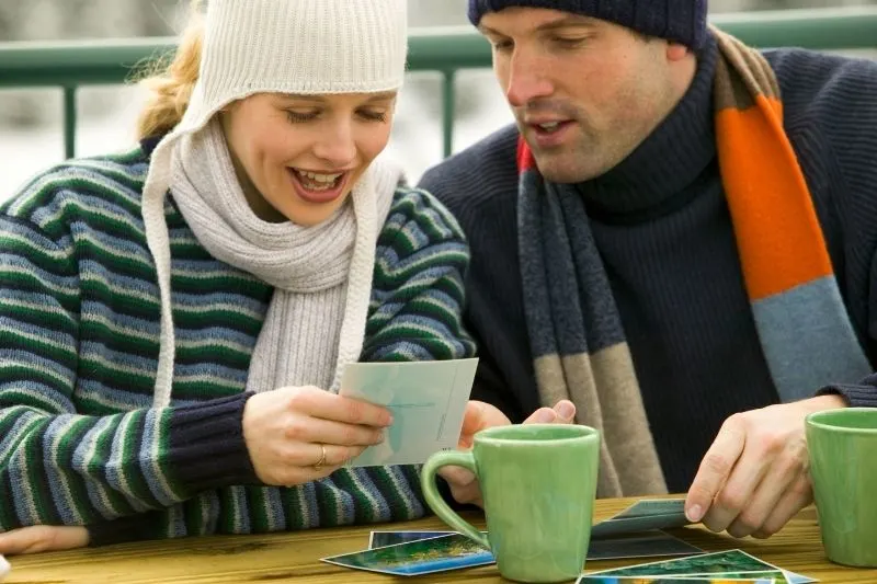 couple looking at pictures outdoors taking coffee while wearing winter clothes