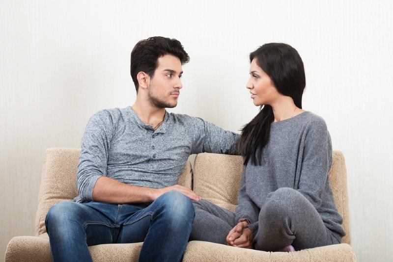 man and woman making eye contact while sitting on sofa