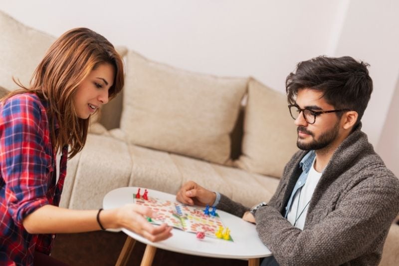 couple playing board game sitting on the living rooms floor