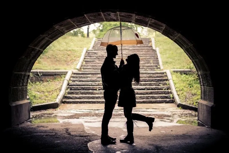 couple under an umbrella during rainy day standing under the bridge