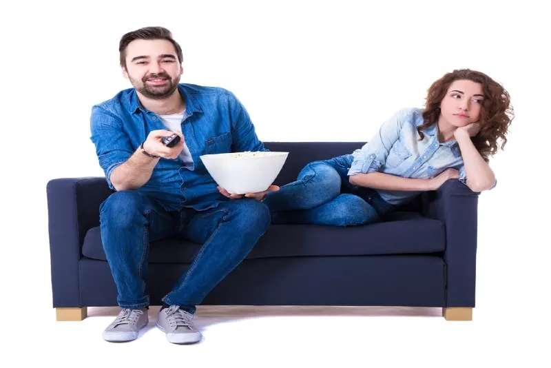 man and woman watching tv while sitting on sofa