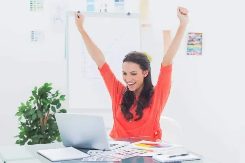 excited woman raising hand looking at her laptop in the office
