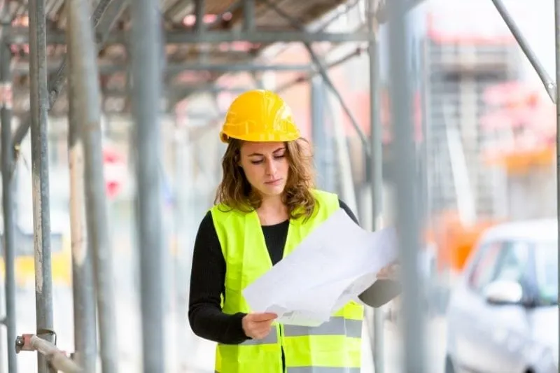 female engineer examining blue print in the construction site