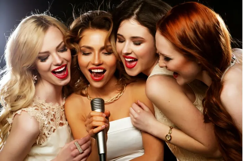 four beautiful stylish girls enjoying karaoke club