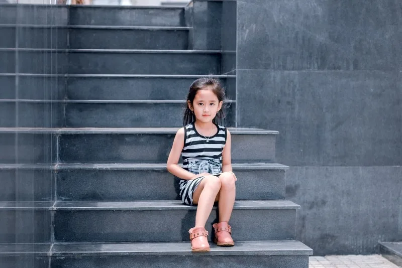 girl in striped dress sitting on stairs