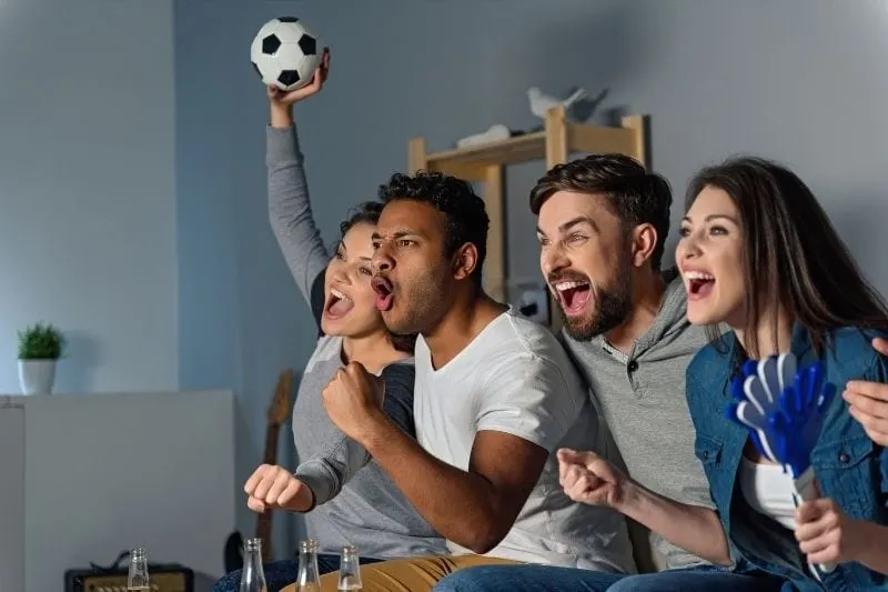 group of friends watching football game with happiness