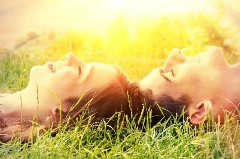 happy young couple in the sun lying down on the grass cropped 
