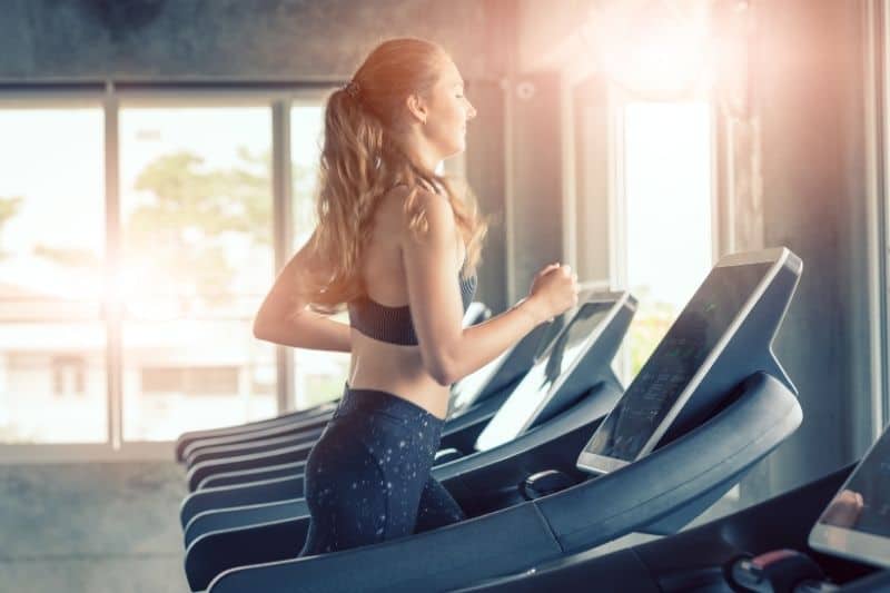 healthy concept of a woman exercising inside the gym jogging in the threadmill