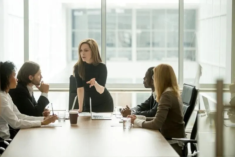 lady boss standing in front of a multiracial colleagues instructing inside the meeting room