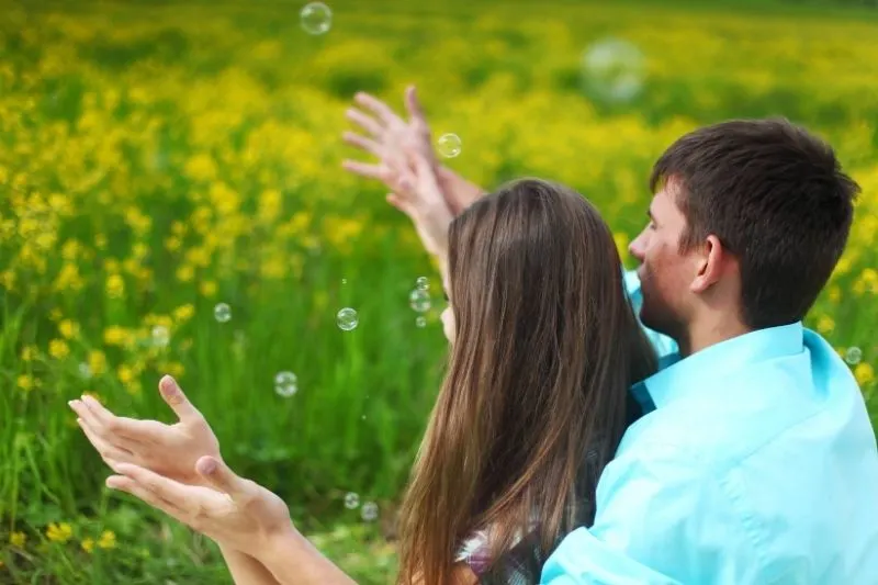 lovers enjoying bubbles in the yellow flower garden
