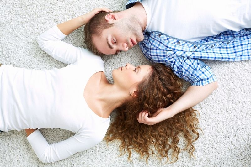 lovers lying down on a rug in opposite directions but face to face