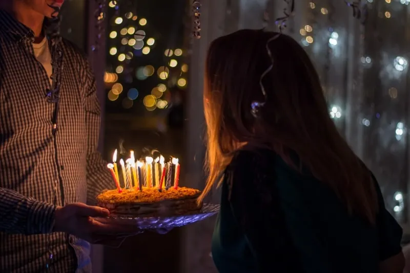 man holding birthday cake while standing near woman