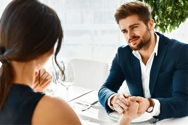 man holding the woman's hand while sitting on table during dinner date