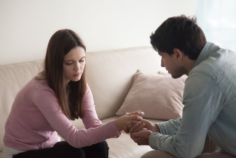 man looking at woman while holding her hands