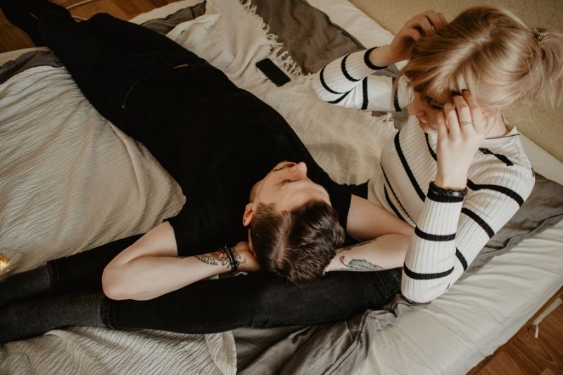 man lying down on the woman's lap inside the room while talking