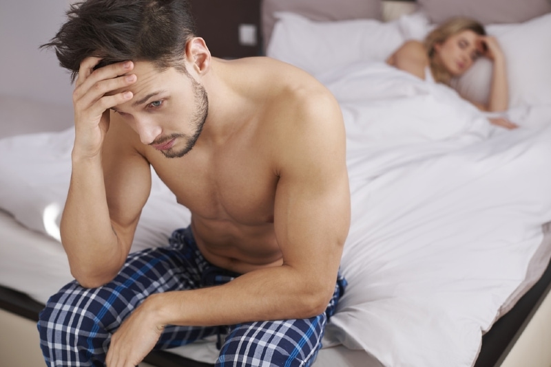 man sitting on bed near sleeping woman