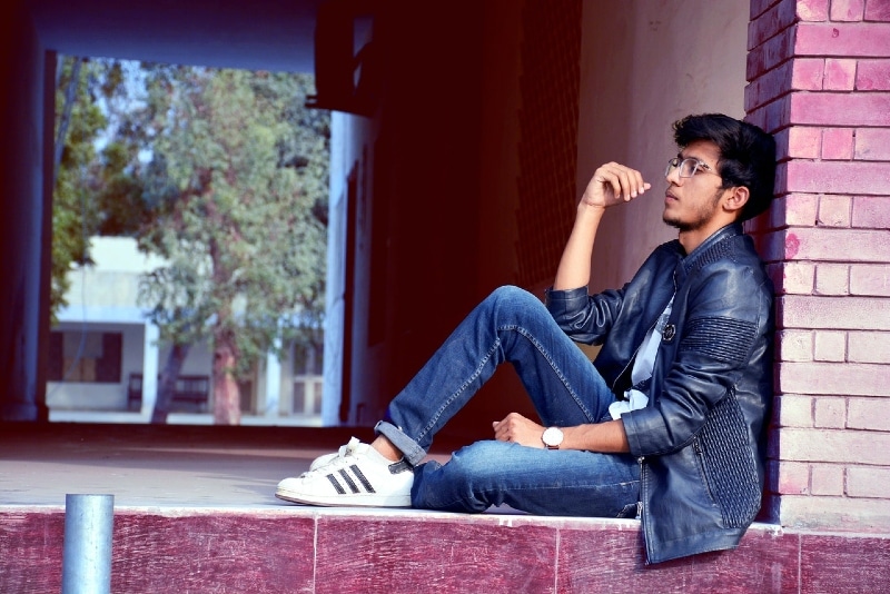 man in denim jacket sitting on floor