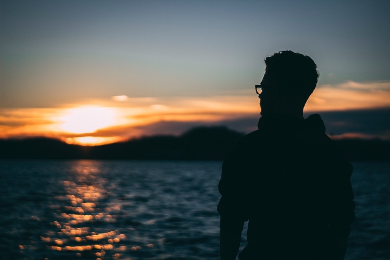 man standing near water during sunrise