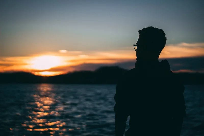 man standing near water during sunrise