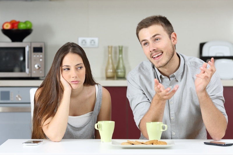 homem feliz a falar com uma mulher enquanto está sentado à mesa