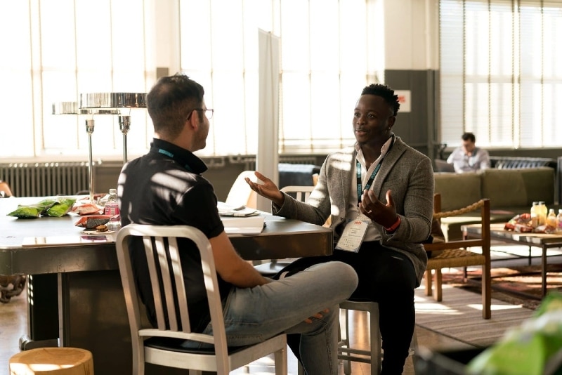 man talking to another man while sitting on chair