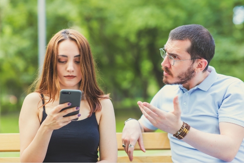 man talking to woman while sitting on bench