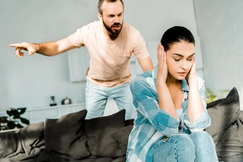 man yelling at woman while standing near sofa