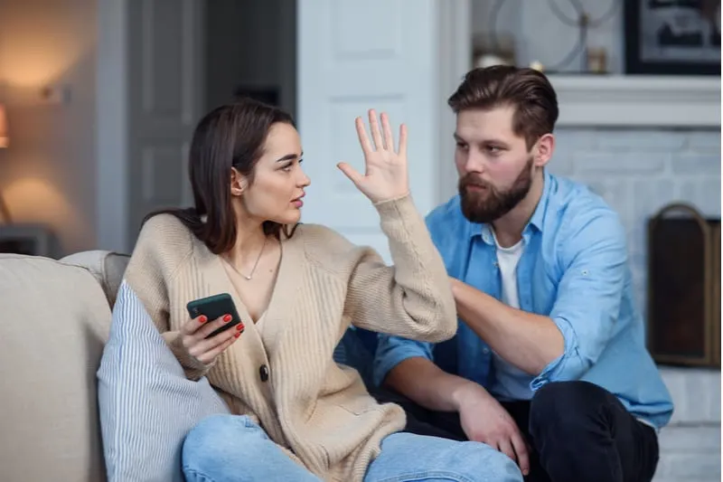 modern couple at home woman ignoring and stopping man from talking as she is busy with phone