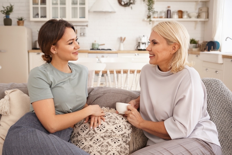 mother and daughter talking while sitting on sofa