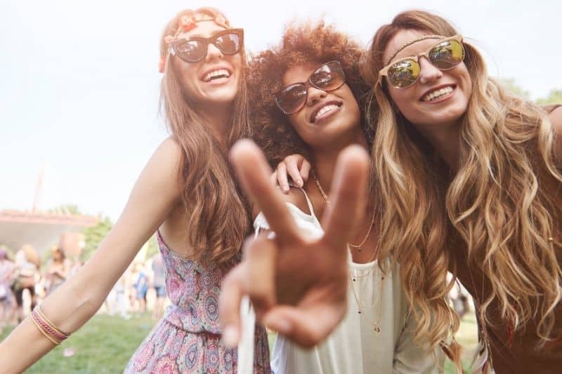 segno di pace con gli amici che indossano occhiali da sole allegro in festa coachella all'aperto