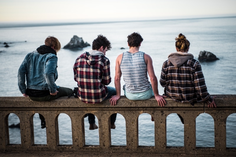 cuatro personas sentadas en un banco mirando al mar