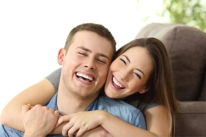 perfect white smile shown by the happy couple hugging inside the livingroom