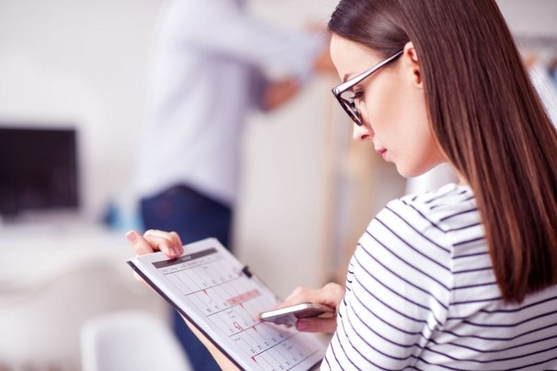 mulher simpática com um calendário na mão a fazer um horário enquanto está sentada