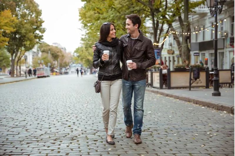 romantic happy couple walking along the street grabbing a cup of coffee