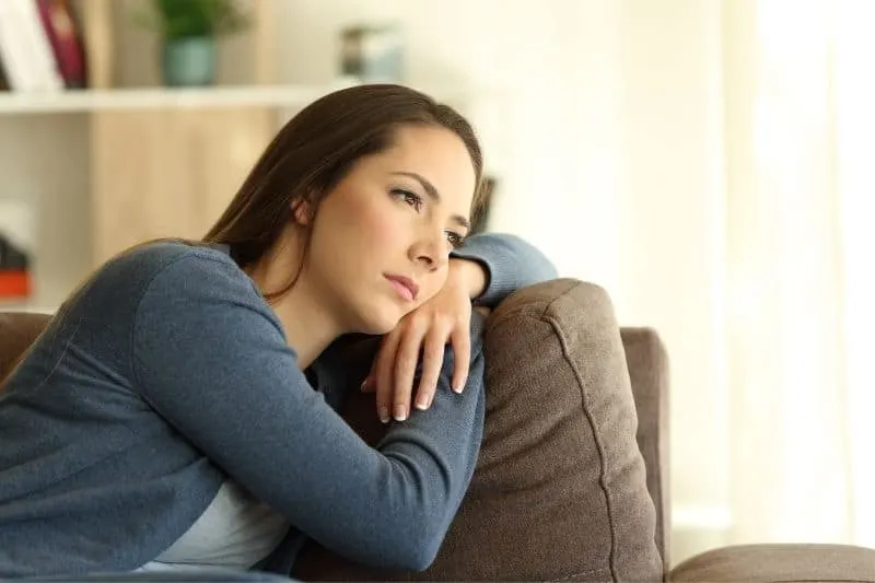 sad woman leaning on couch inside the living room