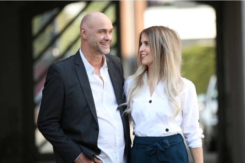 senior man and younger woman couple walking side to side outdoors