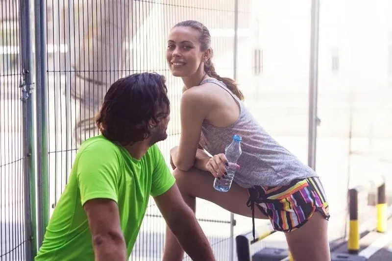sexy young woman exercising with a man looking at her