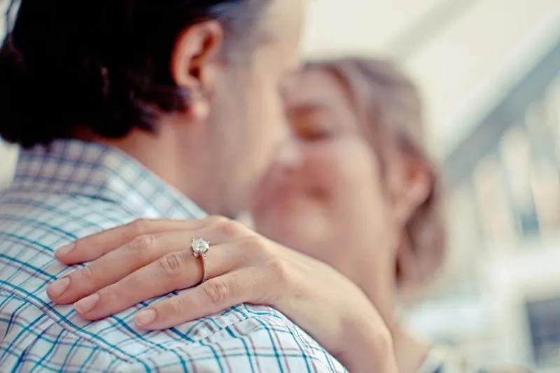 shallow focus photo of couple hugging with focus on the ring on woman's ring finger