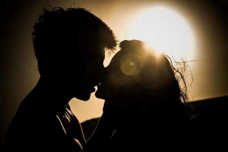 silhouette of couple kissing against the sunset