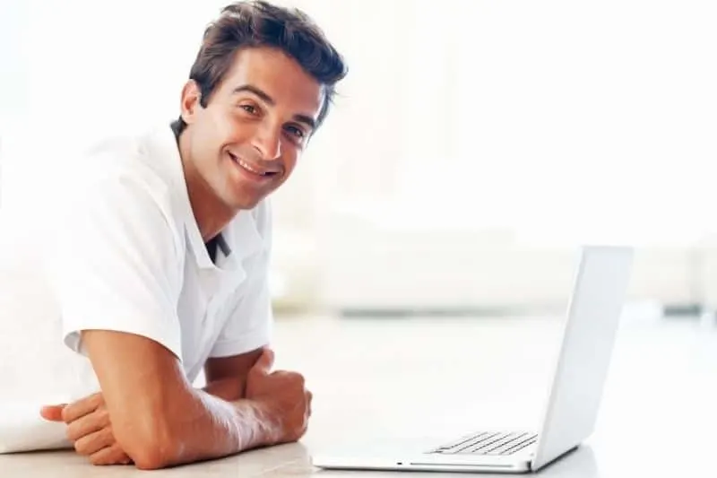 smiling man with laptop looking at the camera during the daytime