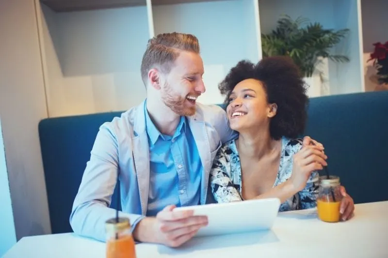 sweet multiracial couple of a red head man and an afro american woman dating inside a cafe