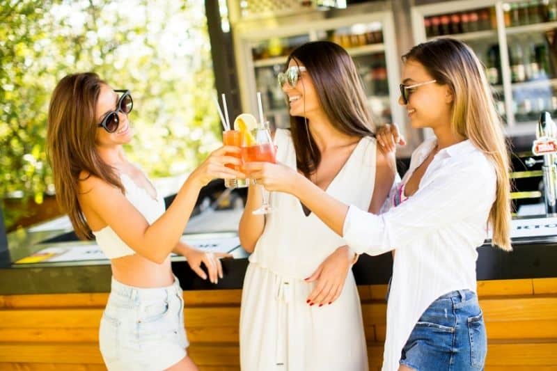 three women drinking cocktail and having fun in a beach bar