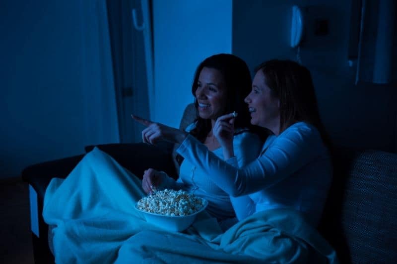duas mulheres a ver televisão no sofá da casa, à noite 