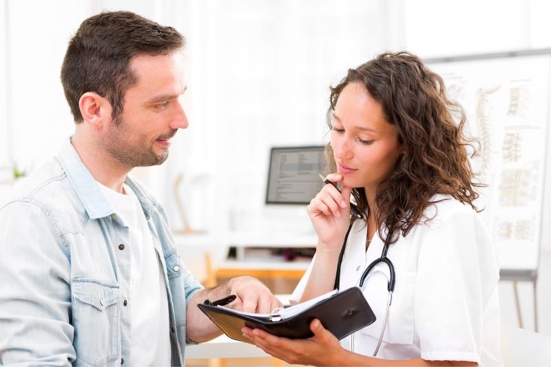 vista de uma jovem médica a sair com um rapaz enquanto olha para a sua agenda dentro da clínica