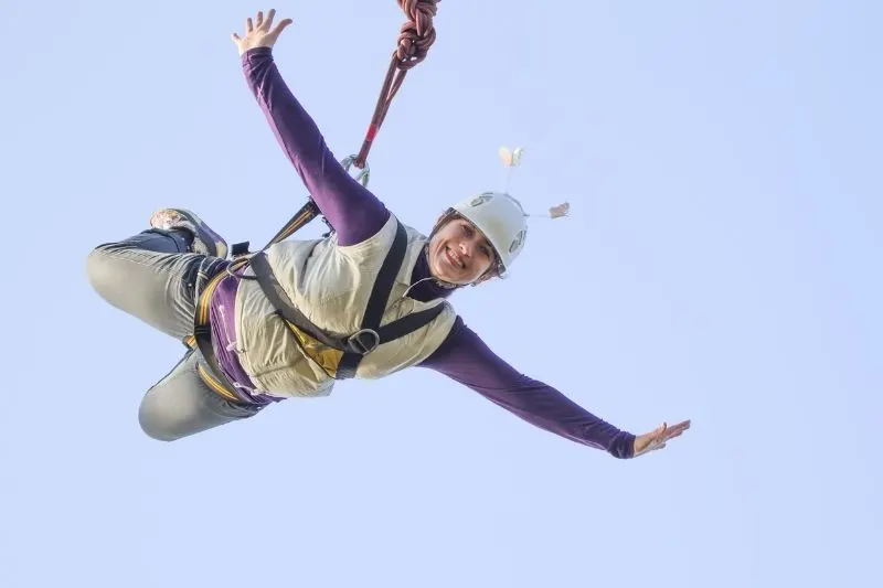 woman bungee jumping smiling against clear blue sky