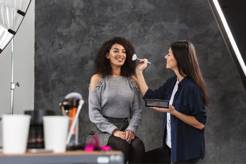 woman doing make up to a model for photoshoot