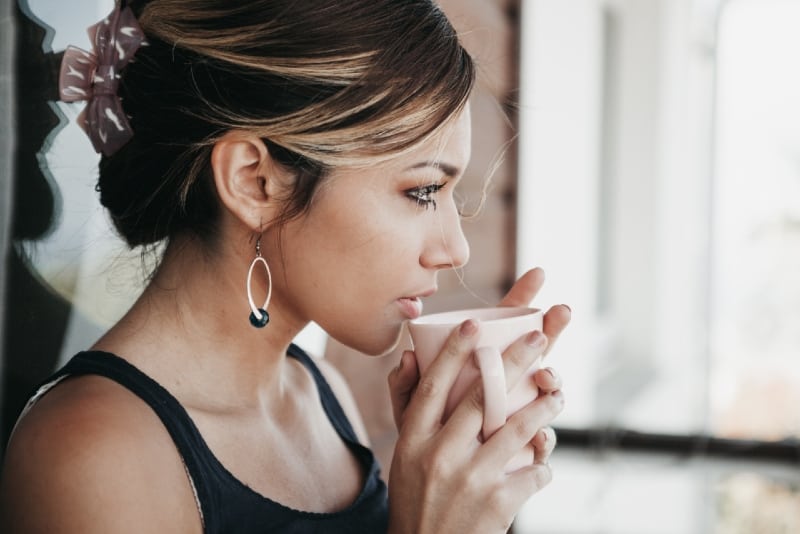 mujer con pendientes bebiendo café