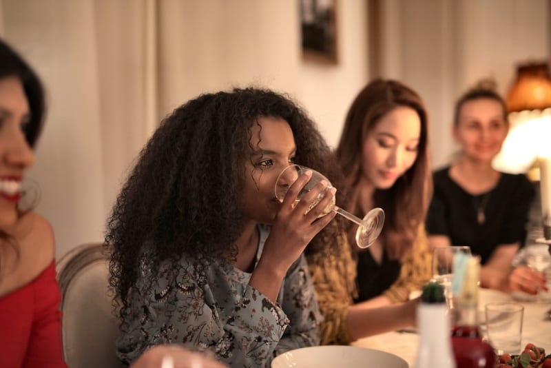 donna che beve vino seduta a tavola