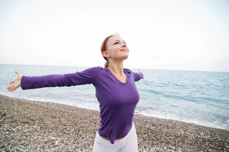 woman enjoying peace and tranquility in the beach raising her arms