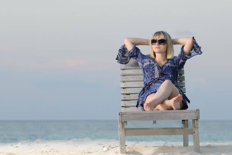 mujer disfruta de la tranquilidad relajandose en la silla en la playa